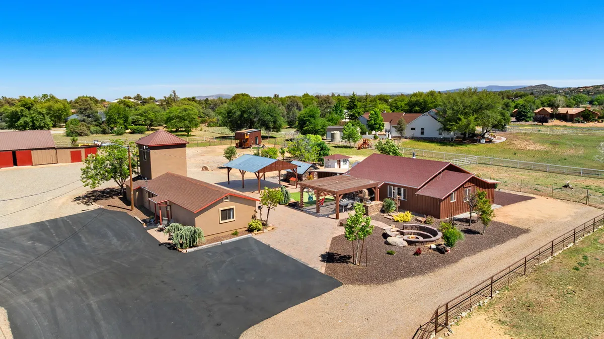 A wide exterior view of the main house features an outdoor patio, lush gardens, and a parking area, all surrounded by nature. The spacious patio and gardens seamlessly transition from home to the great outdoors, inviting guests to relax after a day of adventure.