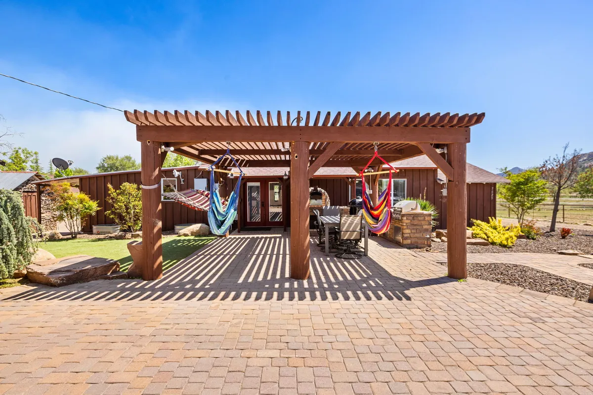 A landscaped outdoor garden area features a pergola with hammocks and comfortable seating. The space is designed for relaxation, offering sunset views and a peaceful retreat surrounded by greenery—perfect for stargazing or sharing stories after a day outdoors.
